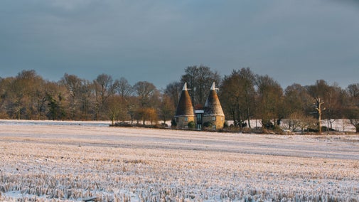 Oasthouses at Ightham Mote with a snowy field in front of them